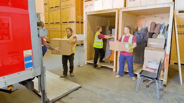Moving crew carrying boxes between storage crates during a pack out