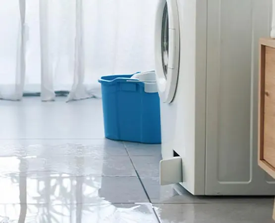 Washing machine leaking water across a laundry room floor