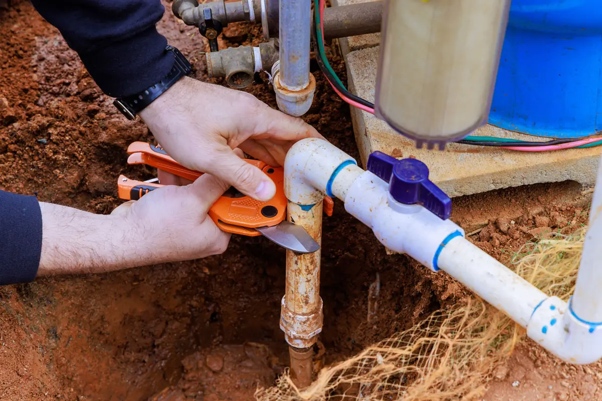Plumber repairing a burst water pipe with professional tools